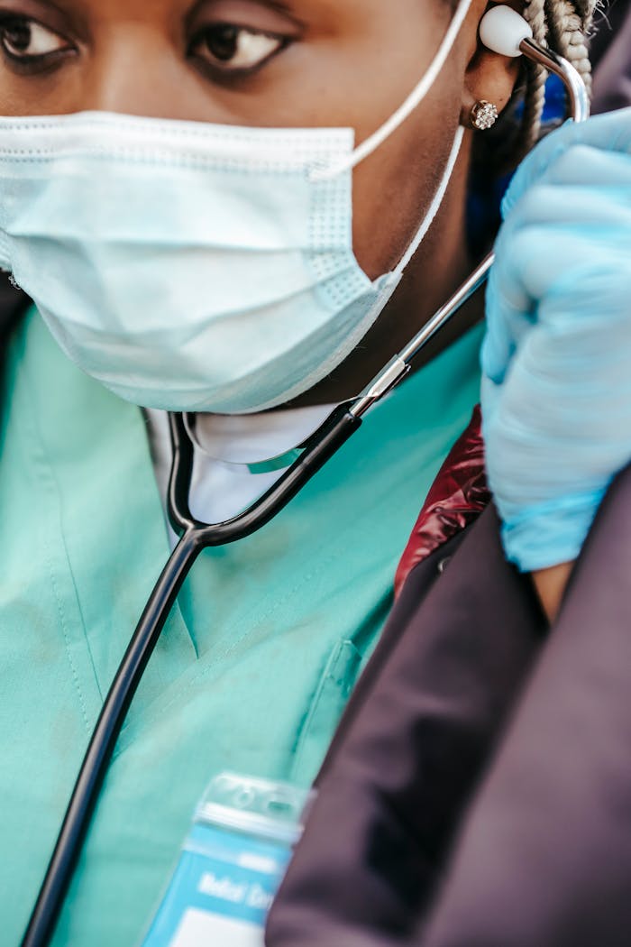 Black woman doctor in mask putting on stethoscope